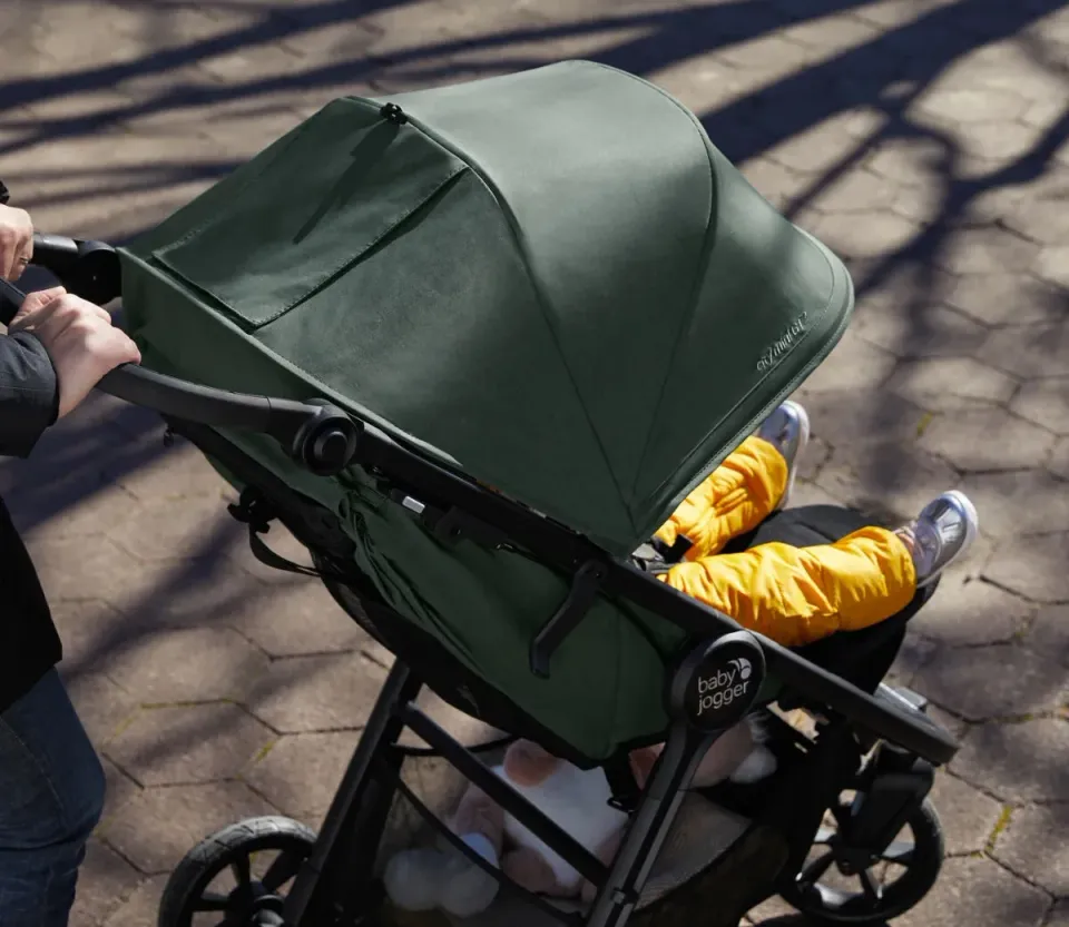 Sulkyn Baby Jogger City Mini GT 2.1 när någon är ute och går med den. Suffletten har fin grön färg.