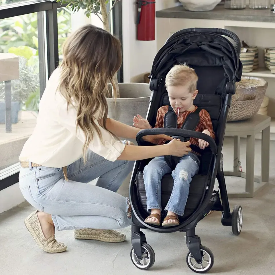 Här ses en mamma och barn som sitter i sulkyvagnen Baby Jogger City Tour 2, denna barnvagn är utmärkt för resor tack vare sin lätta vikt och smidiga hopfällning.