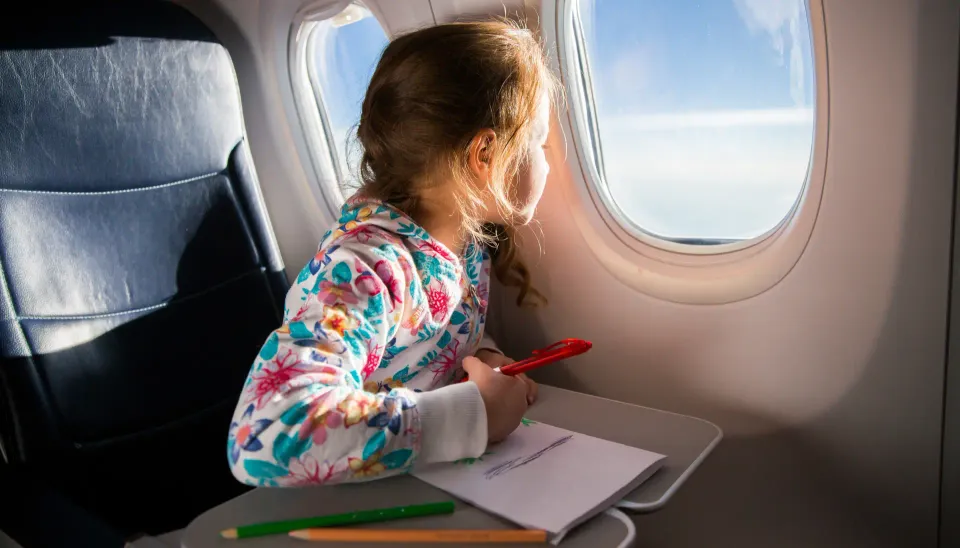 Ett barn som sitter och ritar teckningar på ett flygplan. Det är en utmärkt syssla för att barn att göra när man flyger.