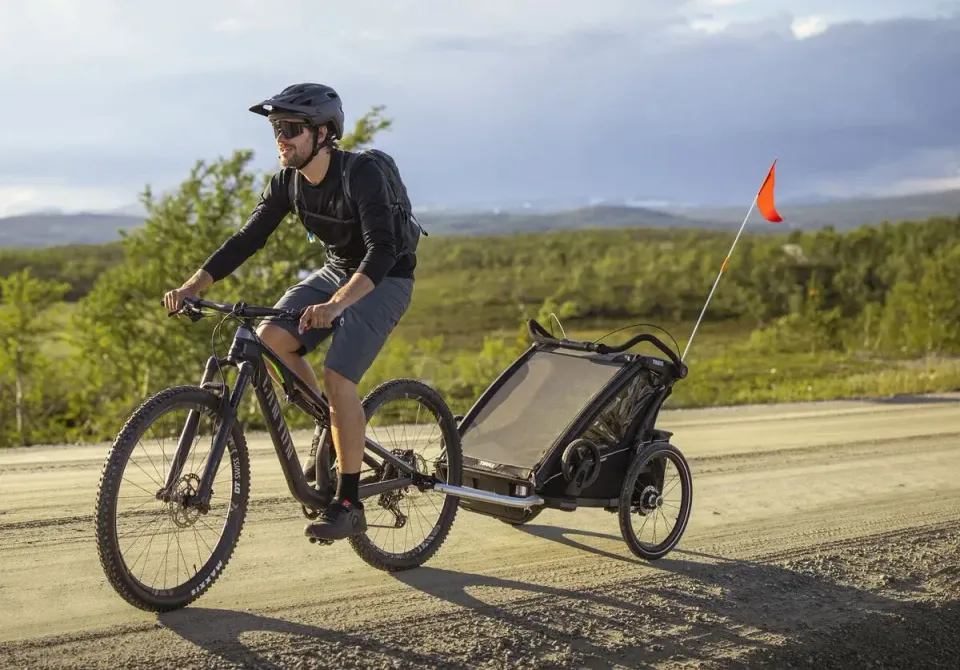 Här syns cykelvagnen Thule Chariot Sport 2 bakom en cykel.